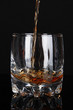 Brandy pouring into glass on black background