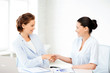 businesswomen shaking hands in office
