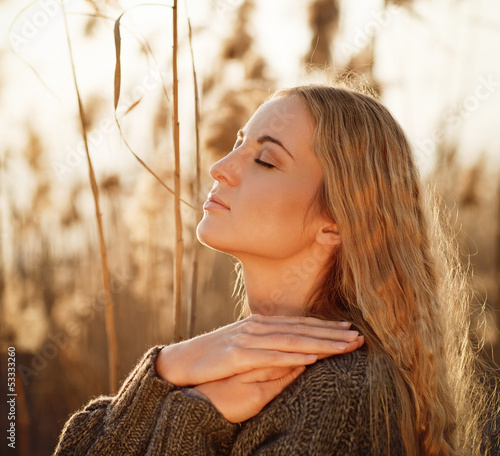 Photo: Portrait of a smiling blond woman relaxing outdoors in a autumn Portrait of a smiling blond woman relaxing outdoors in a autumn