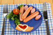 Sausage, greens, tomato on plate on wooden table