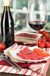 Photo: Tasty salami on plates on wooden table on window background Tasty salami on plates on wooden table on window background