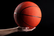 Basketball in woman hand on black background