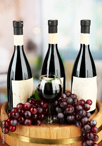 Photo: Composition of wine bottles, glass and grape,on wooden barrel, Composition of wine bottles, glass and grape,on wooden barrel,