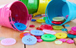 Colorful buttons strewn from buckets close-up