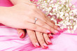 Hands and ring and flowers on a pink background