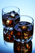 Brandy glasses with ice on blue background