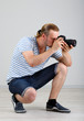 Handsome photographer with camera, on gray background