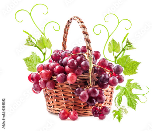 Photo: Red grapes in wicker basket with leaves Isolated on white Red grapes in wicker basket with leaves Isolated on white