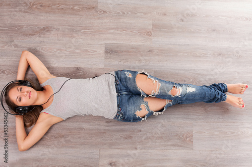 Photo: Woman lying on a floor with headphones Woman lying on a floor with headphones