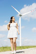 Teen girl next to wind turbine.