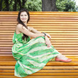 Brunette sitting on a bench in a summer park