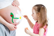 Photo: cute kid girl painting mother's belly cute kid girl painting mother's belly