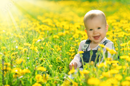 Photo: happy baby girl on meadow with yellow flowers on the nature happy baby girl on meadow with yellow flowers on the nature