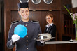Foto: Hotelpage hält leeres Schild an Rezeption Hotelpage hält leeres Schild an Rezeption