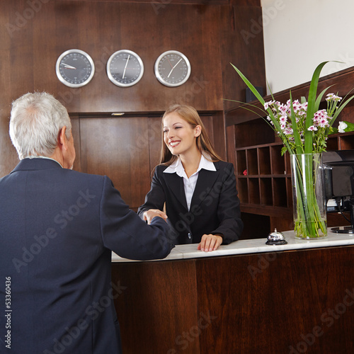 Photo: Empfangsdame begrüßt Senior im Hotel Empfangsdame begrüßt Senior im Hotel