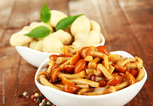 Photo: Mushrooms in bowls, on wooden background Mushrooms in bowls, on wooden background