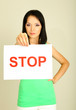 Girl showing stop sign on grey background
