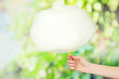 Hand holding stick with cotton candy, on bright background