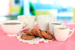 Photo: Cups of coffee with cookies on pink napkin on window background Cups of coffee with cookies on pink napkin on window background