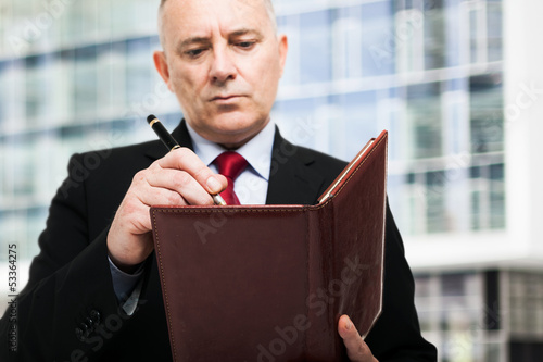 Photo: Businessman writing on his agenda Businessman writing on his agenda