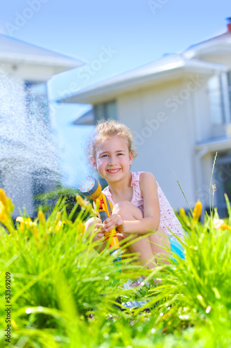 Photo: Little girl watering flowers Little girl watering flowers