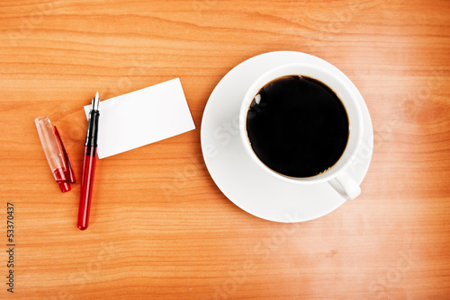 Photo: coffee cup, piece of paper and pen on the wooden table coffee cup, piece of paper and pen on the wooden table