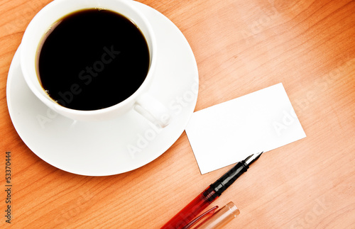 Photo: coffee cup, piece of paper and pen on the wooden table coffee cup, piece of paper and pen on the wooden table