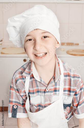 Photo: portrait of a happy little chef in a cap and apron in the portrait of a happy little chef in a cap and apron in the