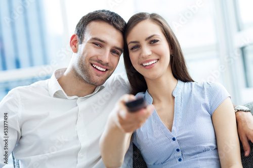 Photo: Young couple with TV remote Young couple with TV remote