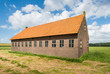 Old barn in a rural landscape with a blue sky and white clouds.