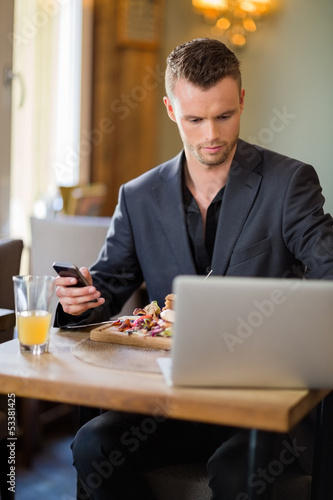 Photo: Businessman With Cellphone And Laptop In Restaurant Businessman With Cellphone And Laptop In Restaurant