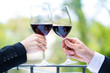 Hands holding red wine glasses to clink