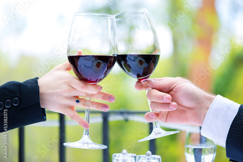 Photo: Hands holding red wine glasses to clink Hands holding red wine glasses to clink