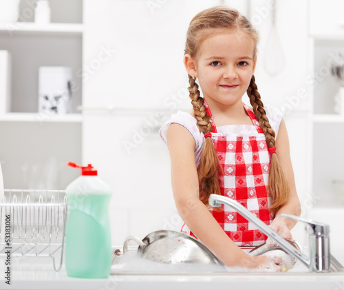 Photo: Little girl washing dishes in the kitchen Little girl washing dishes in the kitchen