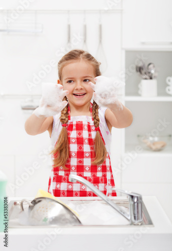 Photo: Happy little girl washing the dishes Happy little girl washing the dishes