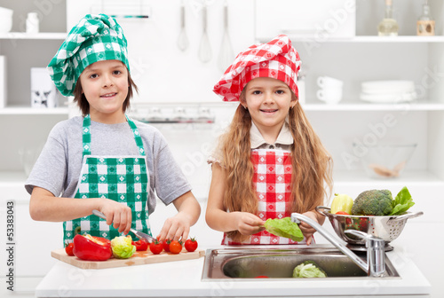 Photo: Kids helping in the kitchen - washing and slicing vegetables Kids helping in the kitchen - washing and slicing vegetables