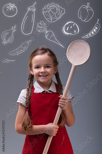 Photo: Young girl with apron and large wooden spoon Young girl with apron and large wooden spoon