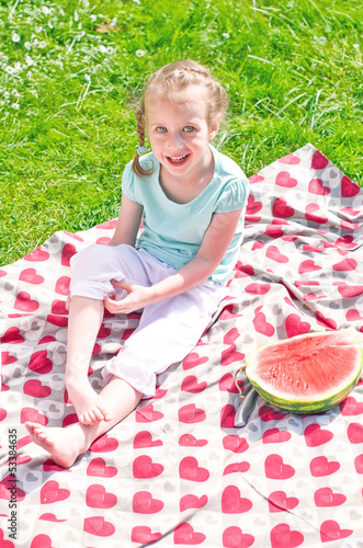 Photo: Little girl sitting on a blanket in the park Little girl sitting on a blanket in the park
