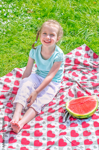 Photo: Little girl sitting on a blanket in the park Little girl sitting on a blanket in the park