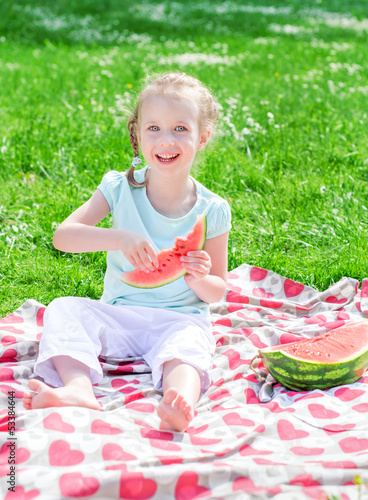 Photo: Pretty little girl eating watermelon in the park Pretty little girl eating watermelon in the park