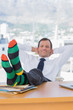 Happy businessman relaxing with feet on his desk