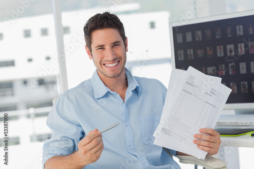 Photo: Cheerful photo editor pointing at documents Cheerful photo editor pointing at documents