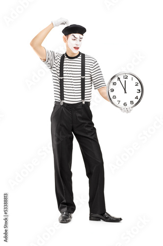 Photo: Full length portrait of a mimic holding a clock and thinking Full length portrait of a mimic holding a clock and thinking