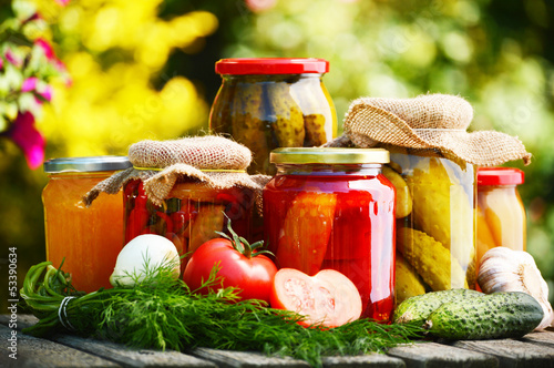 Photo: Jars of pickled vegetables in the garden. Marinated food Jars of pickled vegetables in the garden. Marinated food