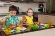 Two children who eat healthy food in the kitchen