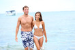 Photo: Beach couple in love walking happy in water Beach couple in love walking happy in water
