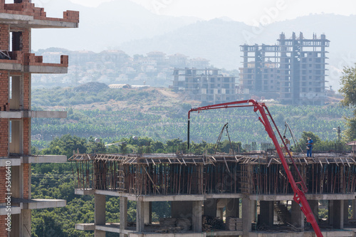 Photo: Worker fills in an armaturny framework of house by concrete Worker fills in an armaturny framework of house by concrete