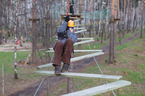 Photo: Little climber goes zigzag obstacle holding safety rope Little climber goes zigzag obstacle holding safety rope