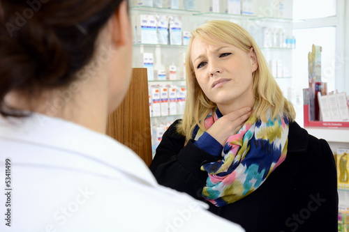 Photo: Junge Frau in Apotheke hat Halsweh Junge Frau in Apotheke hat Halsweh
