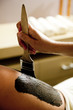 Young woman getting a mud treatment on leg